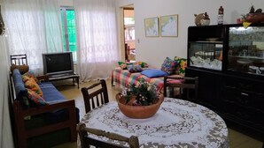 Ein gemütliches Wohnzimmer mit Sofa, Fernseher, Esstisch und einer dekorativen Schale.