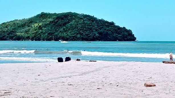 Ein Strand mit einer kleinen Insel im Hintergrund.