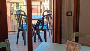 En matplats med ett bord och stolar, utsikt över havet och en balkong med ett räcke.