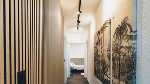 A hallway with a wooden slat wall, a tiled floor, and a ceiling light fixture.