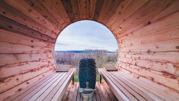 A wooden structure with a semi-circular opening, benches, and a large tire in the center.