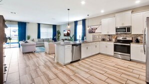 A modern kitchen with white cabinets, stainless steel appliances, and a herringbone wood floor. - MEGA MANSION! Private Theater! Waterpark Near Disney! (Davenport)