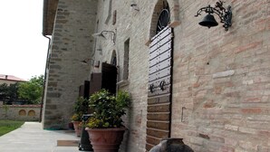 A courtyard with a stone wall, potted plants, a large ceramic pot, and a metal bell. - Historical Residence il Biribino 27 People (Città di Castello)