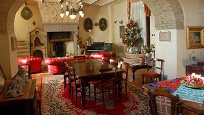 A cozy living room with a fireplace, red leather sofa, wooden dining table, and a Christmas tree. - Historical Residence il Biribino 27 People (Città di Castello)