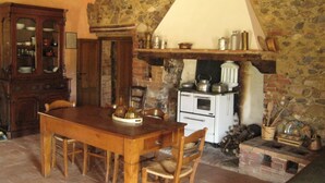 A rustic kitchen with a wooden table, chairs, and a white stove. - la Casa - Agriturismo With Pool Between Siena and Grosseto (Civitella Paganico)