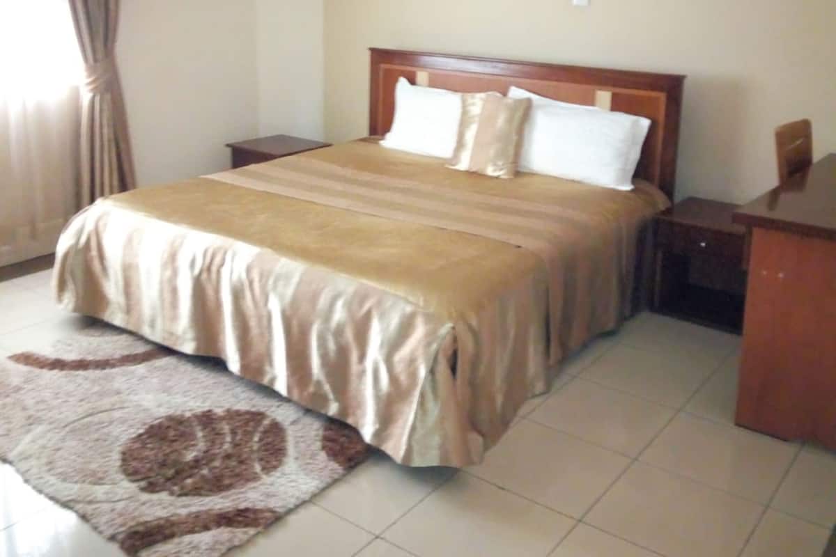 A hotel room with a large bed, a desk, and a nightstand.