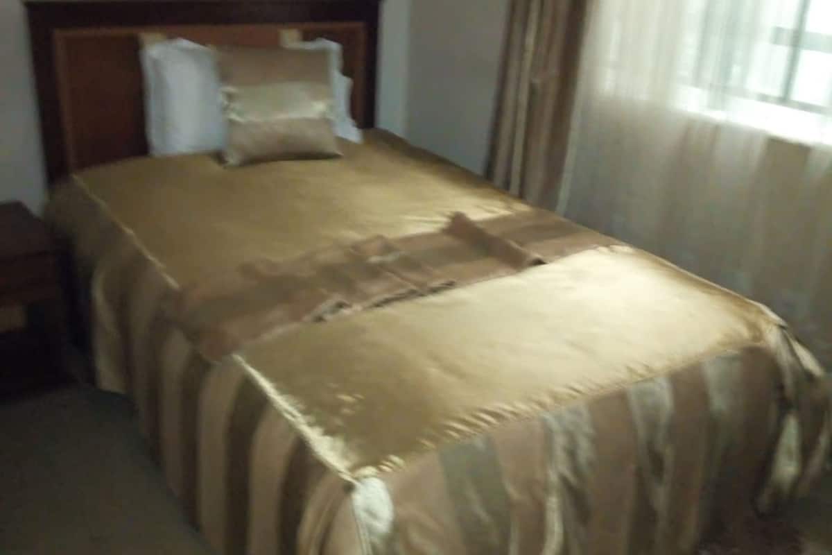 A standard hotel room with a single bed, a nightstand, and a window with curtains.