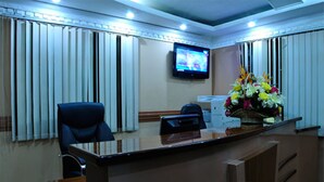 Un mostrador de recepción con televisión, una silla y un arreglo floral.