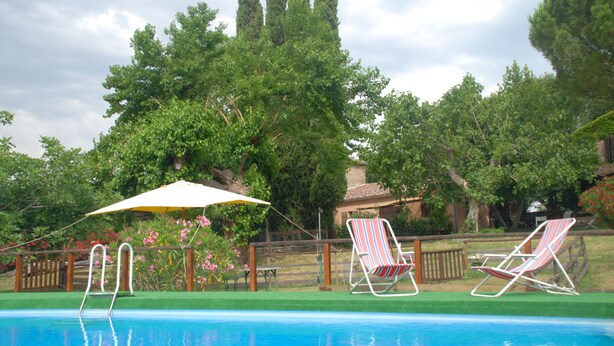 Una piscina con dos sillas de descanso y una sombrilla.