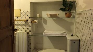 Un baño pequeño con inodoro, lavamanos y una ventana sobre el inodoro.