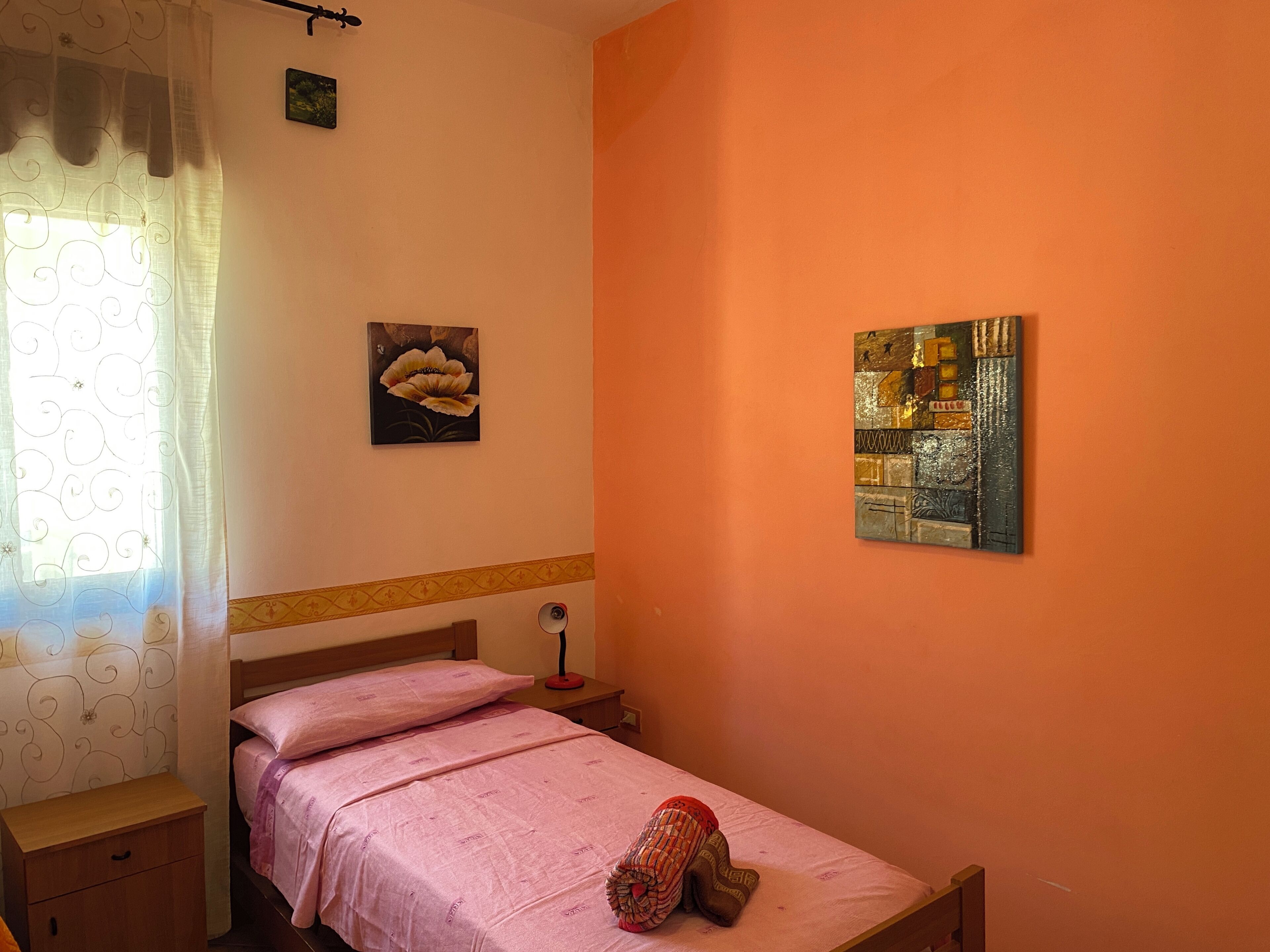 Un dormitorio con una cama, una mesita de noche, una lámpara y dos cuadros en la pared.