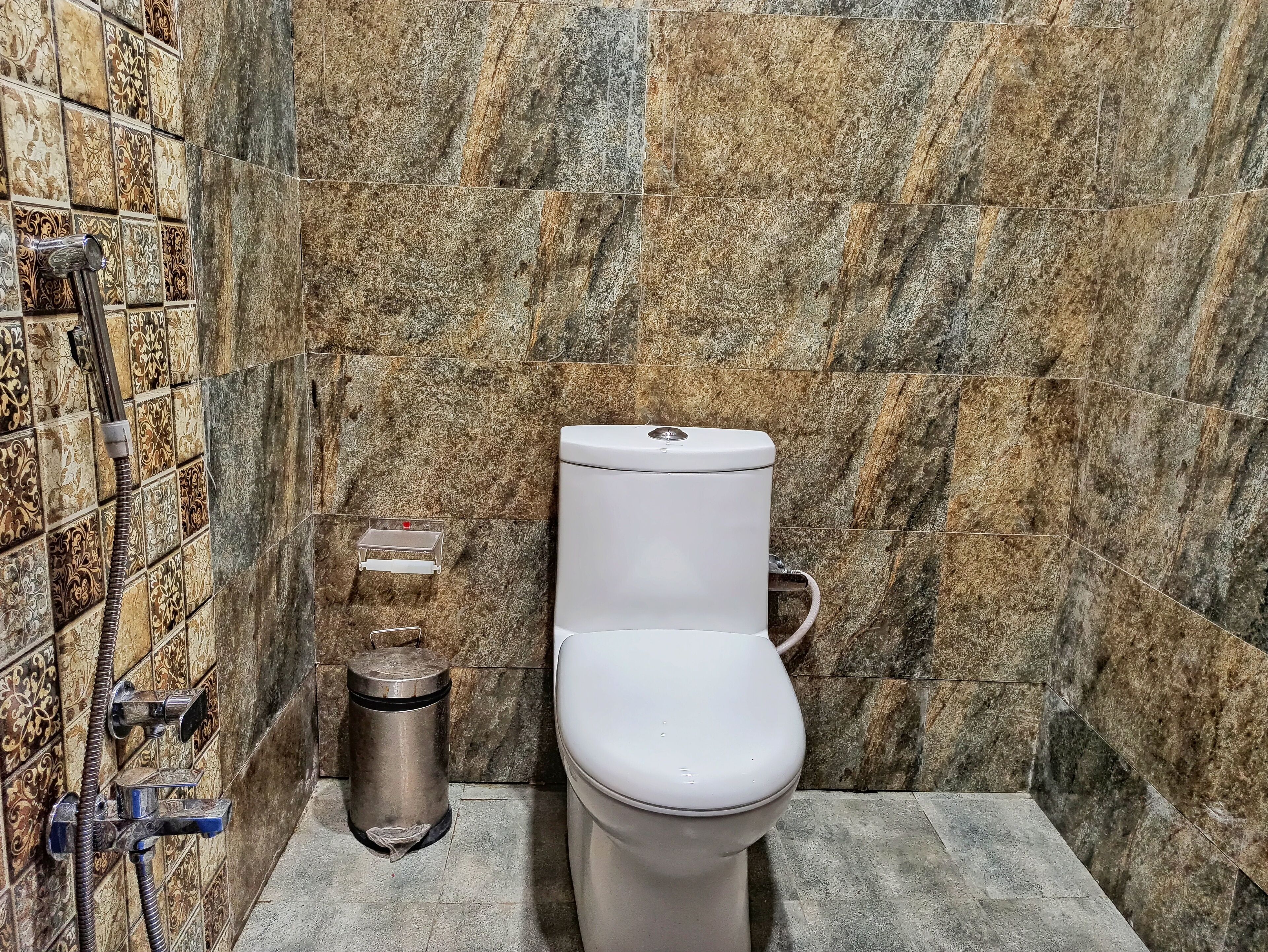 A bathroom with a toilet, a shower, and a trash bin.