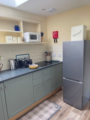 Fully equipped kitchen with a refrigerator, microwave, toaster, sink, and cabinets.