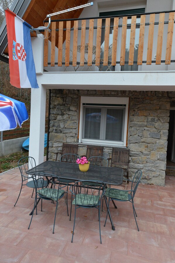 A balcony with wooden railings, a stone wall, and a table with chairs.
