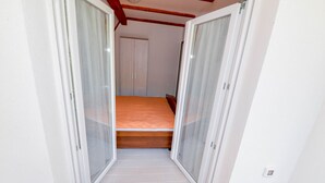 A small bedroom with a bed, a wardrobe, and a sliding door. - Chalet Katarina (Lovinac)