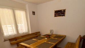A dining area with a wooden table and benches, a window with curtains, and a small framed picture on the wall. - Chalet Katarina (Lovinac)