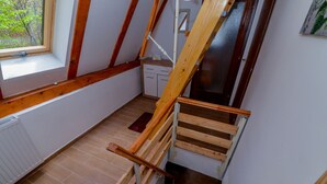 A wooden staircase in a room with a window, a radiator, and a small cabinet. - Chalet Katarina (Lovinac)