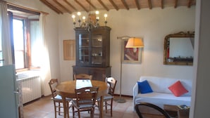A dining area with a wooden table and chairs, a cabinet, a lamp, and a sofa with cushions. - Silence and Relaxation in Countryside of Umbria (Amelia)