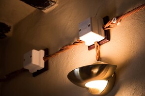 A wall-mounted light fixture with a unique design, including a metal bowl and a rope-like element.
