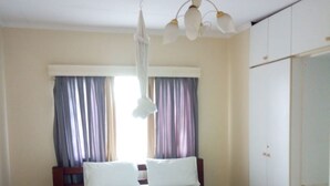 A bedroom with a wooden bed, white curtains, a ceiling fan, and a wardrobe. - South C Bungalow (Nairobi)