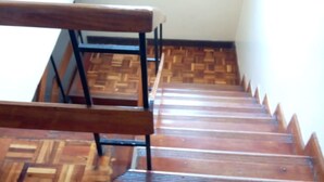 A wooden staircase with a herringbone pattern floor and a metal bench at the top. - South C Bungalow (Nairobi)