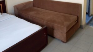 A bedroom with a bed, a brown sofa, and a small table. - South C Bungalow (Nairobi)