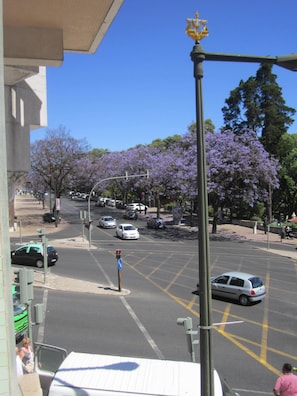 A street view with cars, traffic lights, and trees with purple flowers. - GoodTime Marquês Suites (Lisbon)
