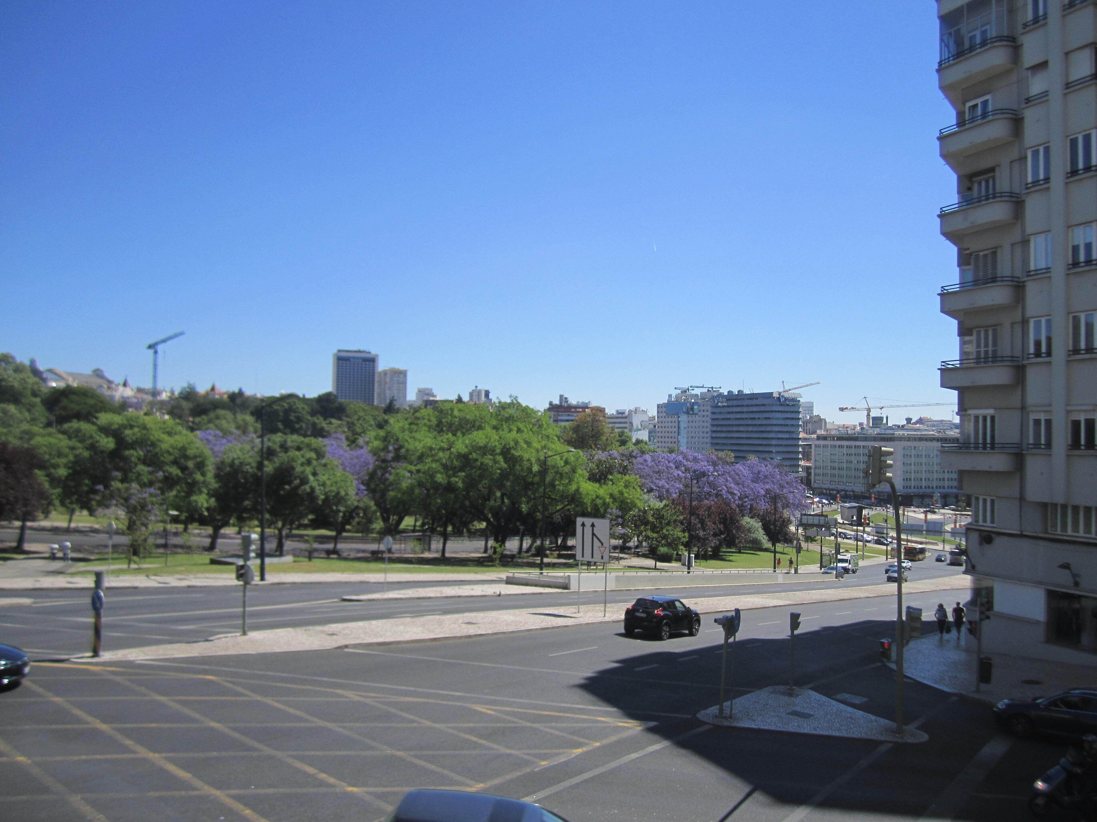 A city intersection with buildings, trees, and a parking lot.