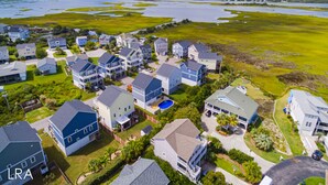A residential area with houses, a swimming pool, and a large body of water in the background. - Beach Bliss & Pool Days Await! (Surf City)
