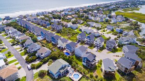 A residential area with houses, a swimming pool, and a beach in the background. - Beach Bliss & Pool Days Await! (Surf City)