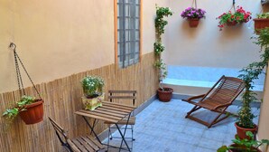 A patio with a wooden table and chairs, potted plants, and a hanging chair. - Tukory - Flat For Rent - City Center Palermo (Palermo)