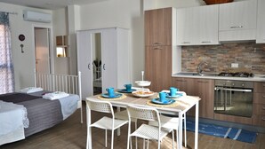 A compact room with a bed, a dining table with chairs, a kitchenette, and a wardrobe. - Tukory - Flat For Rent - City Center Palermo (Palermo)
