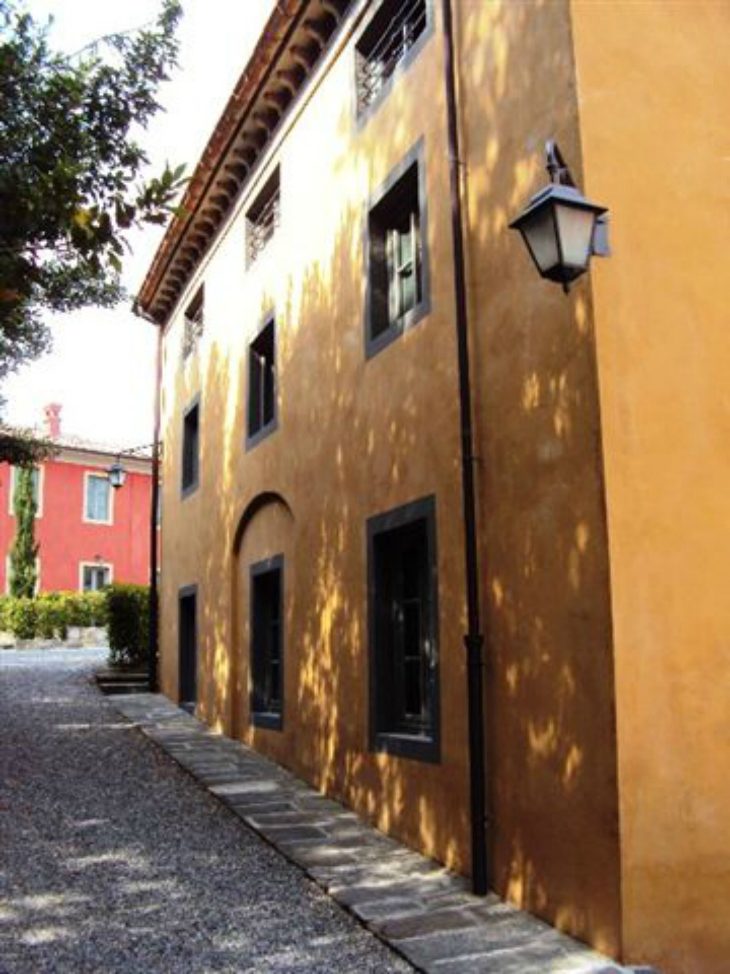 A building with a yellow facade, black windows, and a cobblestone path.