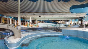 Una piscina interior de diseño curvo, con techo cubierto y un tobogán.