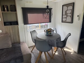 A dining area with a round table, grey chairs, a basket, and a hanging light fixture. - RBR 168 - Beach Resort Kamperland (Kamperland)