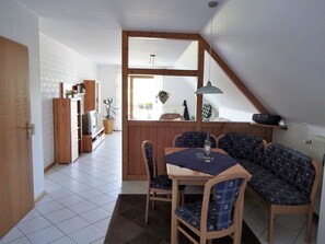 Ein Essbereich mit Tisch und Stühlen, einer Holzbank und Blick durch ein Fenster.