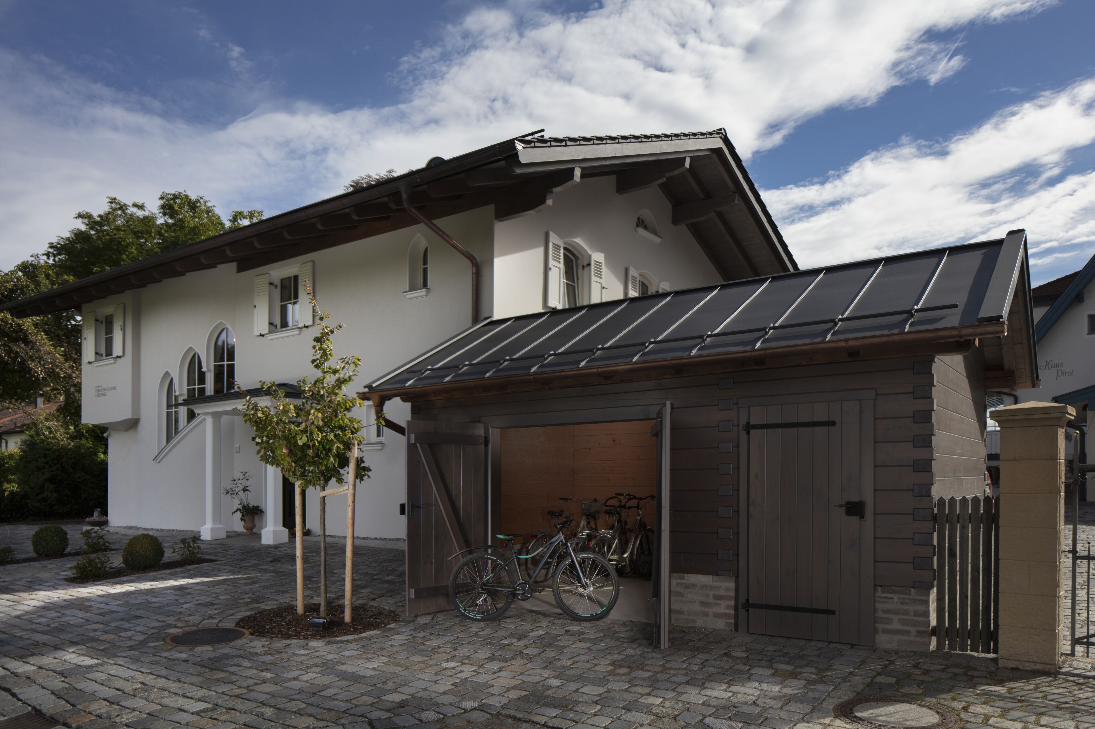 Et hus med garage, cykelskur og en belagt indkørsel.
