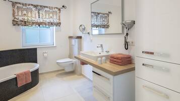 A modern bathroom with a bathtub, toilet, sink, and vanity.