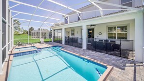 A covered outdoor swimming pool with a patio area, a ceiling fan, and a view of the surrounding landscape.