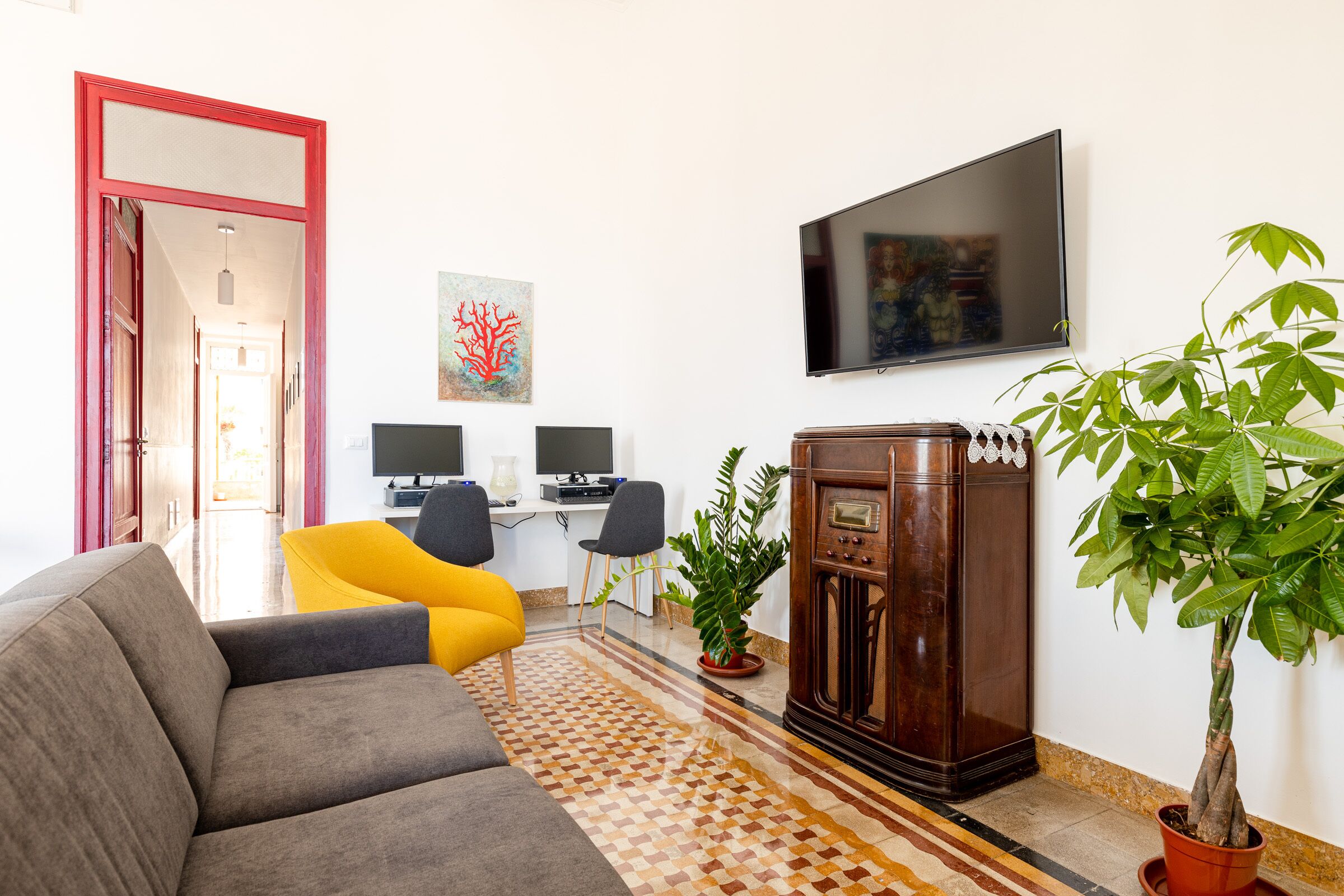 Un saló amb un sofà, una televisió, dues cadires, una taula baixa i una planta en test.