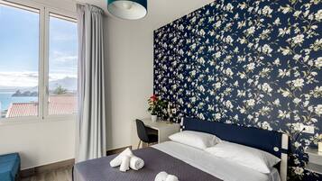 Ein Hotelzimmer mit Bett, Schreibtisch und Meerblick.