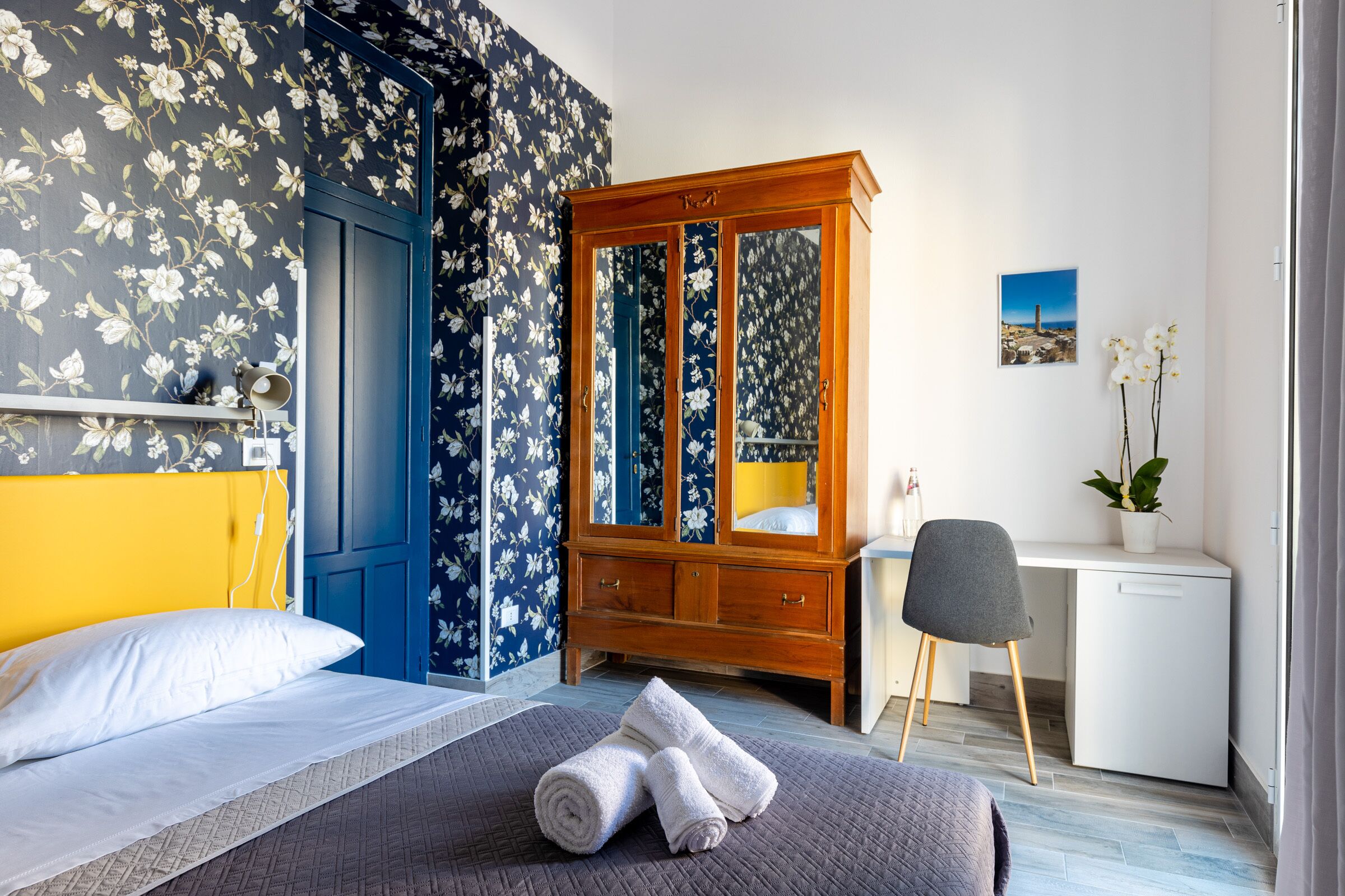 Une chambre d’hôtel avec un lit, un bureau, une armoire et une chaise.