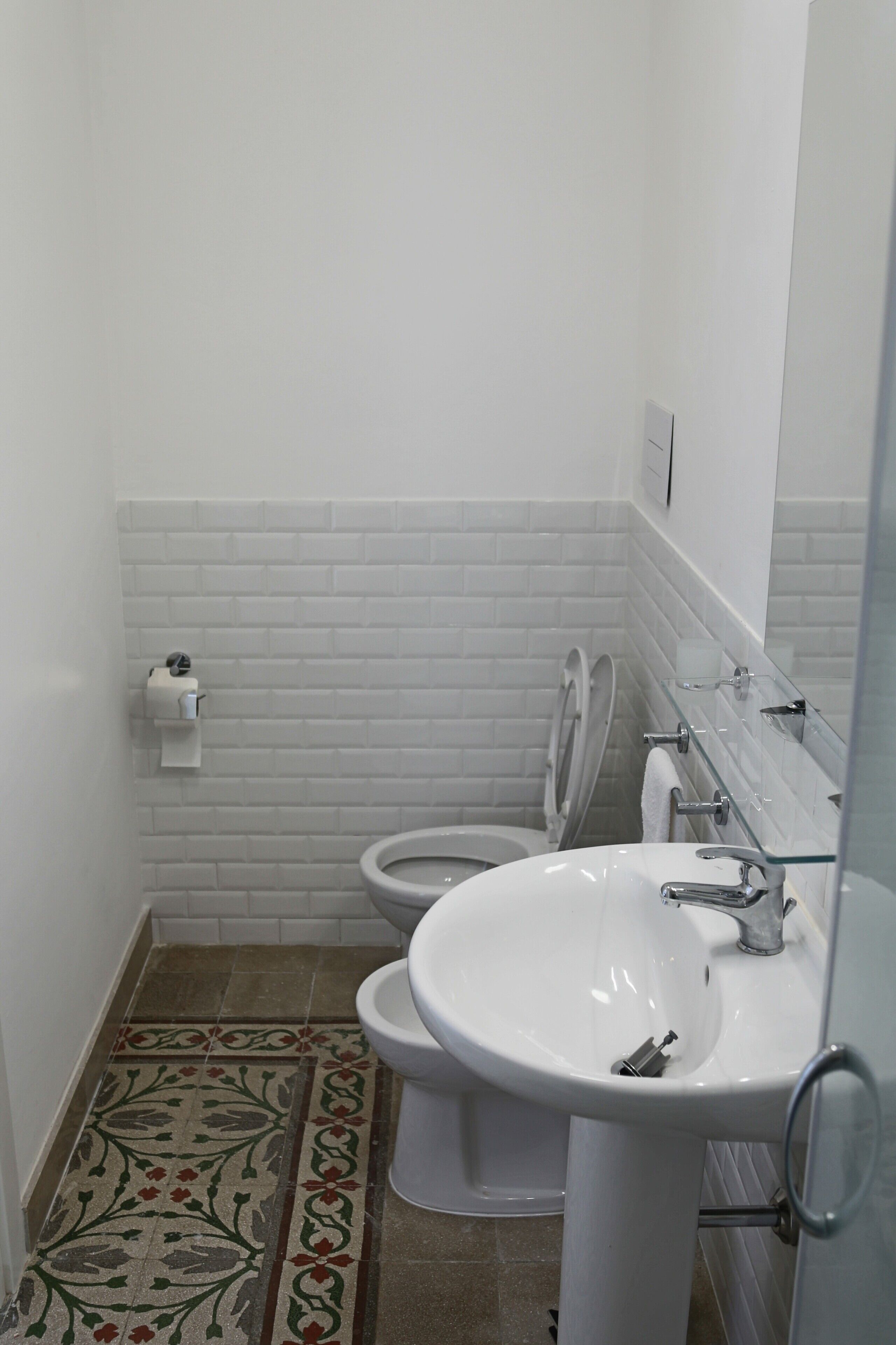 Een badkamer met witte betegelde wanden, een wit wastafel en een toilet.