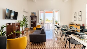 A spacious living area with a sofa, yellow armchair, and a dining table with chairs. - Villa Edera Rental Rooms (Santa Flavia)
