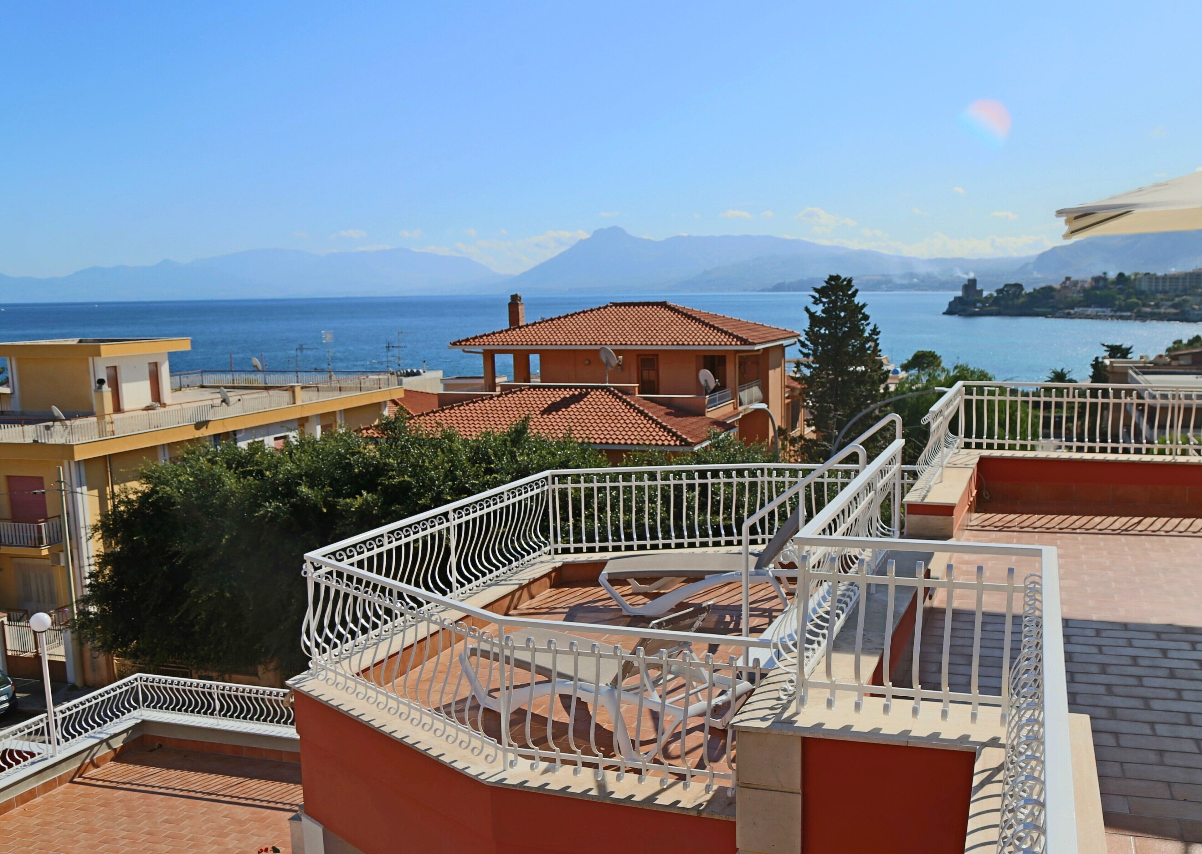 Un quartier résidentiel offrant une vue sur la mer, avec une maison au toit rouge et une balustrade blanche.