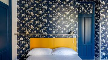 A bedroom with a bed, a yellow headboard, and floral wallpaper.