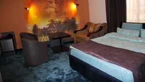 A hotel room with a large bed, two armchairs, a small table, and a wall mural. - Nice Hotel Yerevan (Yerevan)