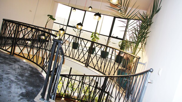 A staircase with a metal railing, potted plants, and hanging pendant lights. - Nice Hotel Yerevan (Yerevan)