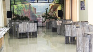A modern interior with wooden chairs arranged in rows, a polished floor, and a mural on the wall depicting a street scene. - Nice Hotel Yerevan (Yerevan)