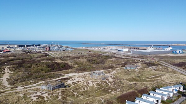 A coastal industrial area with buildings, a marina, and a sandy landscape.